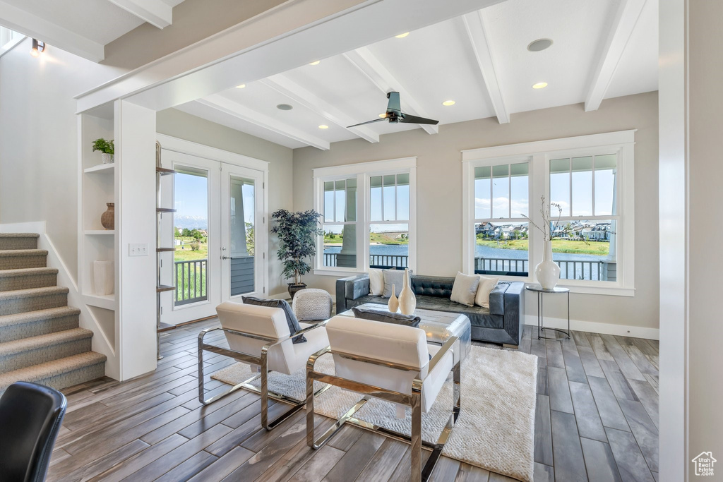 Living room featuring french doors, healthy amount of natural light, beamed ceiling, wood finished floors, and stairway
