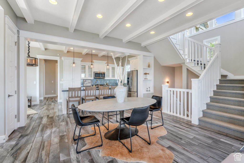 Dining area featuring wood finished floors, baseboards, recessed lighting, beamed ceiling, and stairs