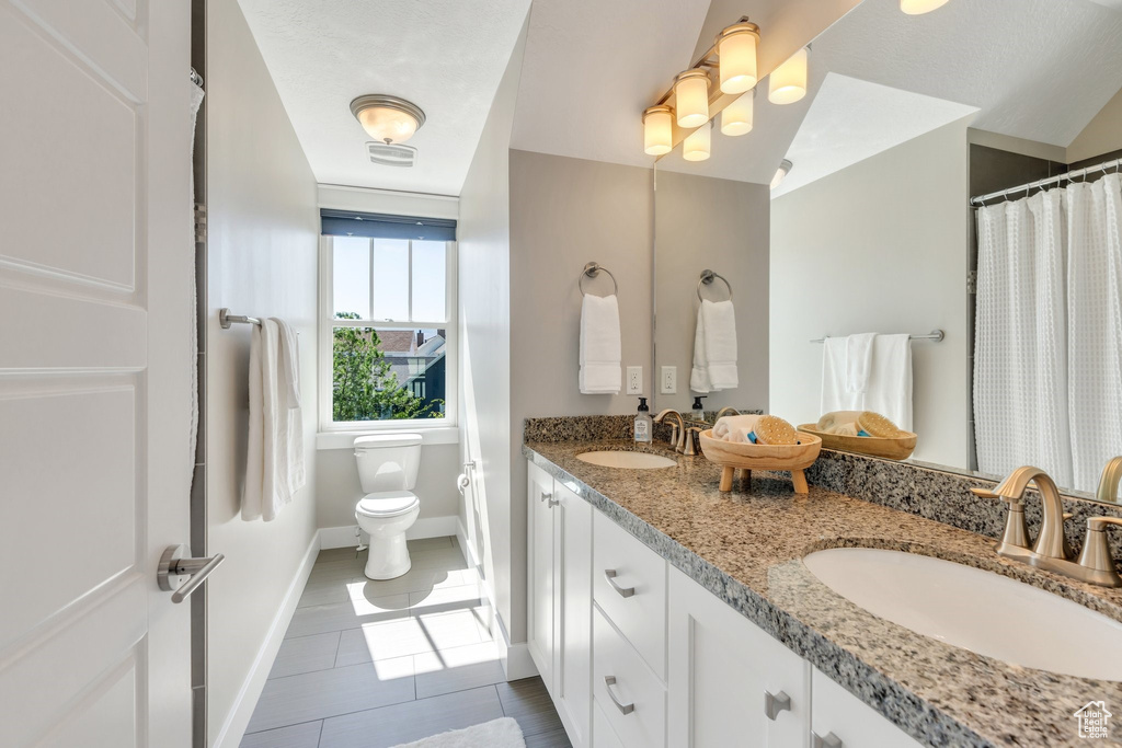 Bathroom with double vanity, baseboards, toilet, tile patterned flooring, and a shower with curtain