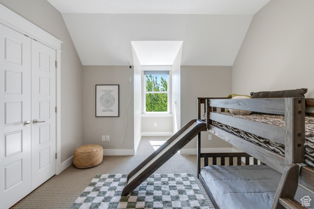 Carpeted bedroom with lofted ceiling and baseboards