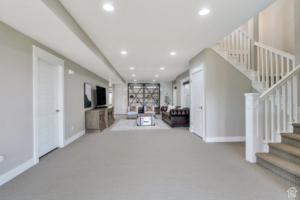 Unfurnished living room with carpet floors, baseboards, recessed lighting, and stairway