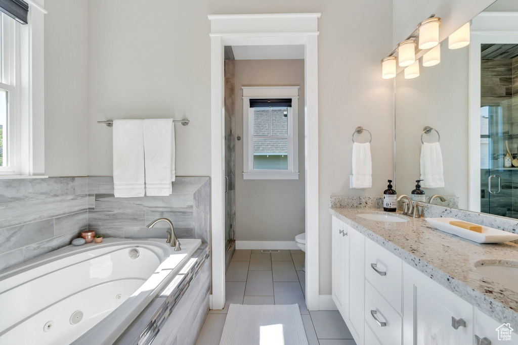 Bathroom featuring a stall shower, double vanity, a whirlpool tub, and tile patterned flooring