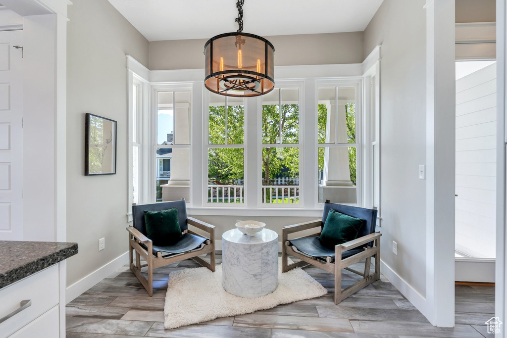 Sitting room with a chandelier, baseboards, and light wood-type flooring