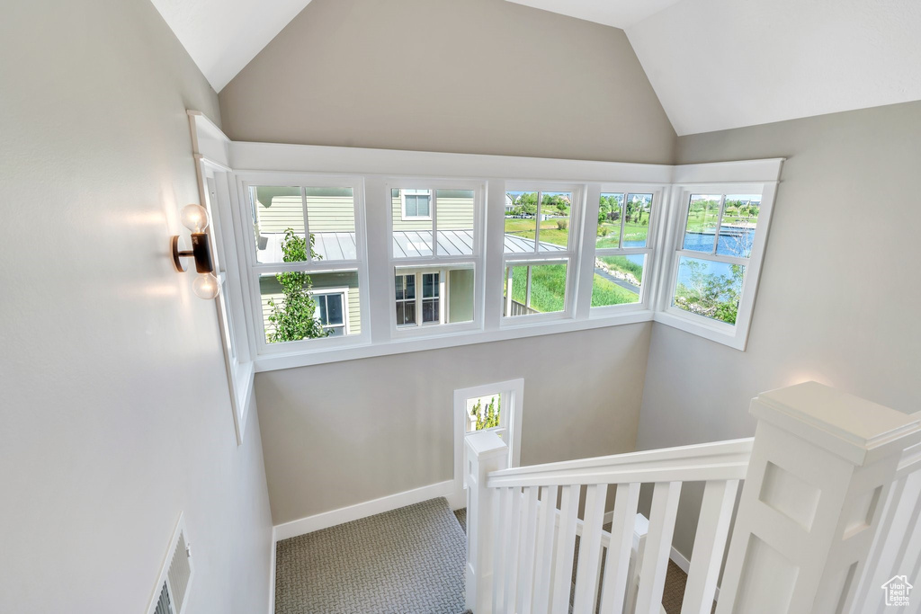 Stairway featuring lofted ceiling, carpet, plenty of natural light, and baseboards