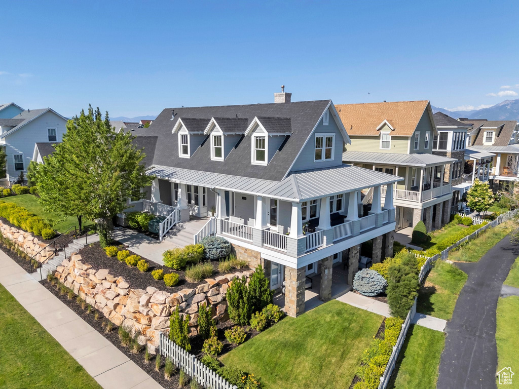View of front of property with a standing seam roof, metal roof, stone siding, a residential view, and a chimney