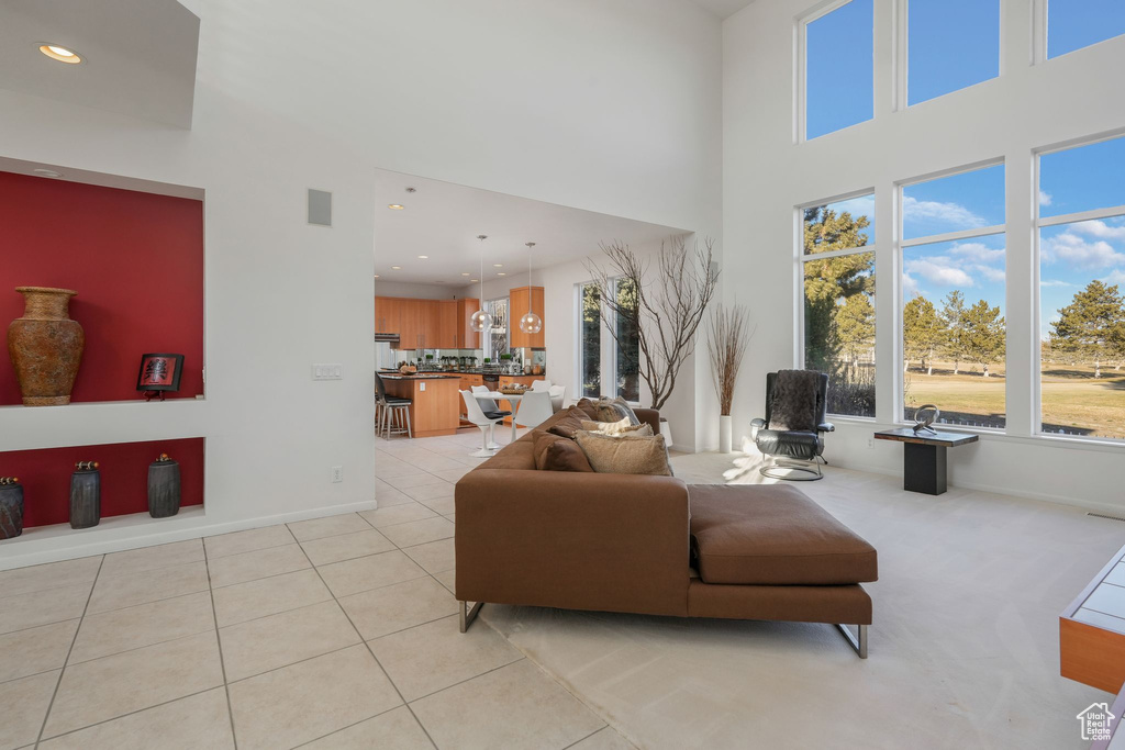 Living room with a high ceiling, recessed lighting, light tile patterned floors, and baseboards