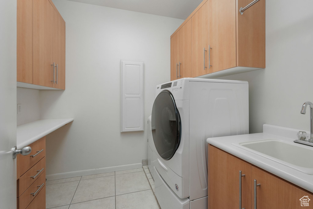 Laundry area with washer / clothes dryer, cabinet space, light tile patterned floors, and baseboards