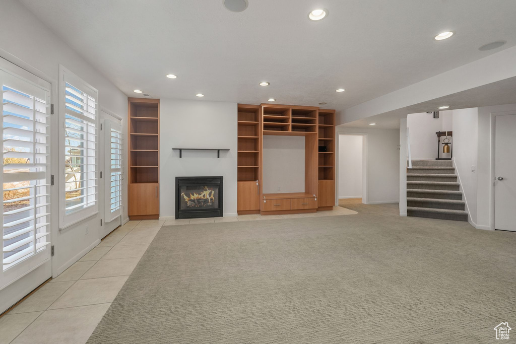 Unfurnished living room featuring recessed lighting, stairs, a glass covered fireplace, light tile patterned flooring, and baseboards