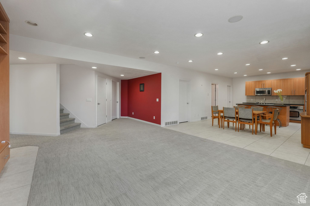Living room with recessed lighting, light colored carpet, baseboards, stairway, and light tile patterned floors
