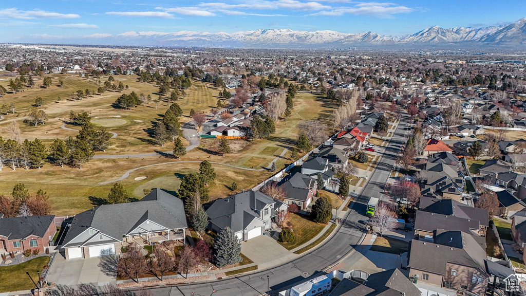 Aerial overview of property's location featuring nearby suburban area, a mountainous background, and a golf club