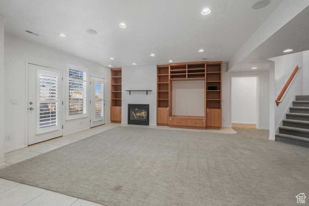 Unfurnished living room with recessed lighting, stairway, baseboards, a fireplace with flush hearth, and light tile patterned floors