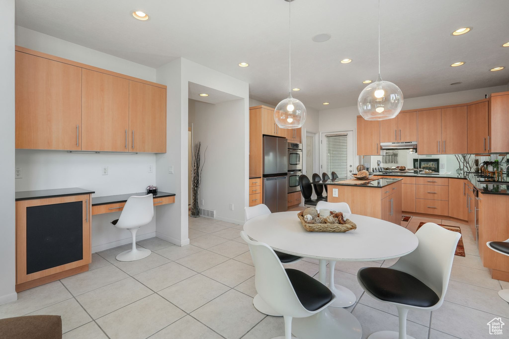 Kitchen with stainless steel appliances, recessed lighting, under cabinet range hood, dark countertops, and light tile patterned flooring