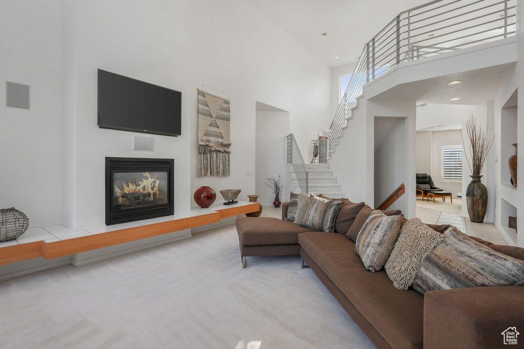Living room with a towering ceiling, stairway, and a glass covered fireplace