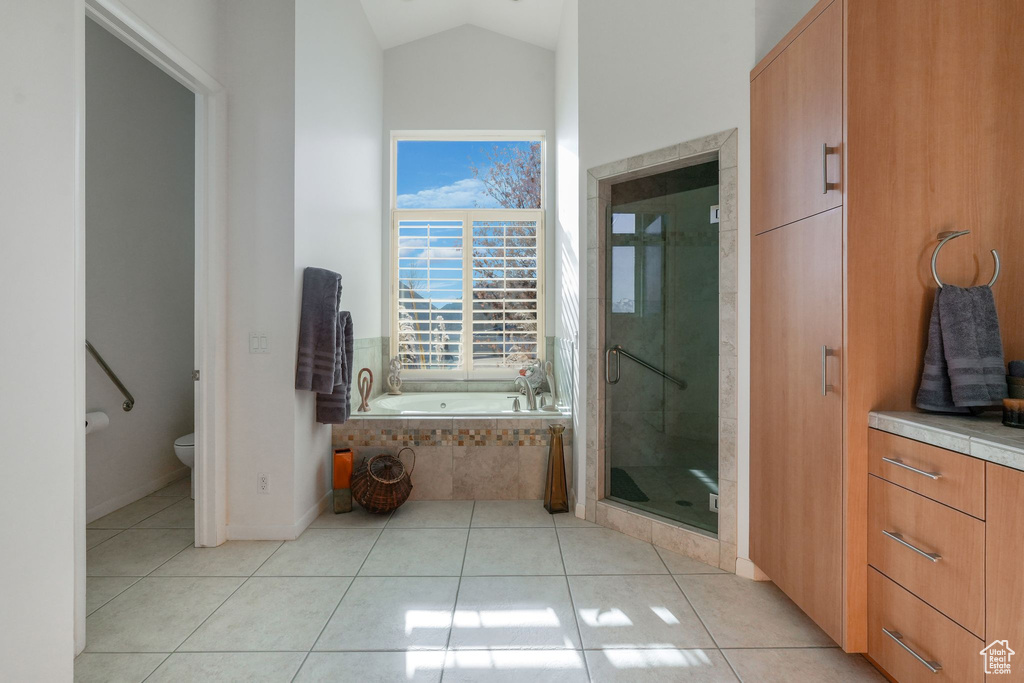 Bathroom with tile patterned floors, a garden tub, toilet, a stall shower, and vaulted ceiling