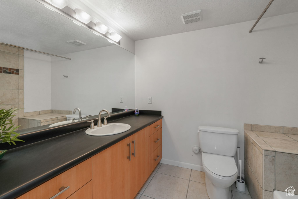 Bathroom with vanity, toilet, tile patterned floors, a textured ceiling, and baseboards