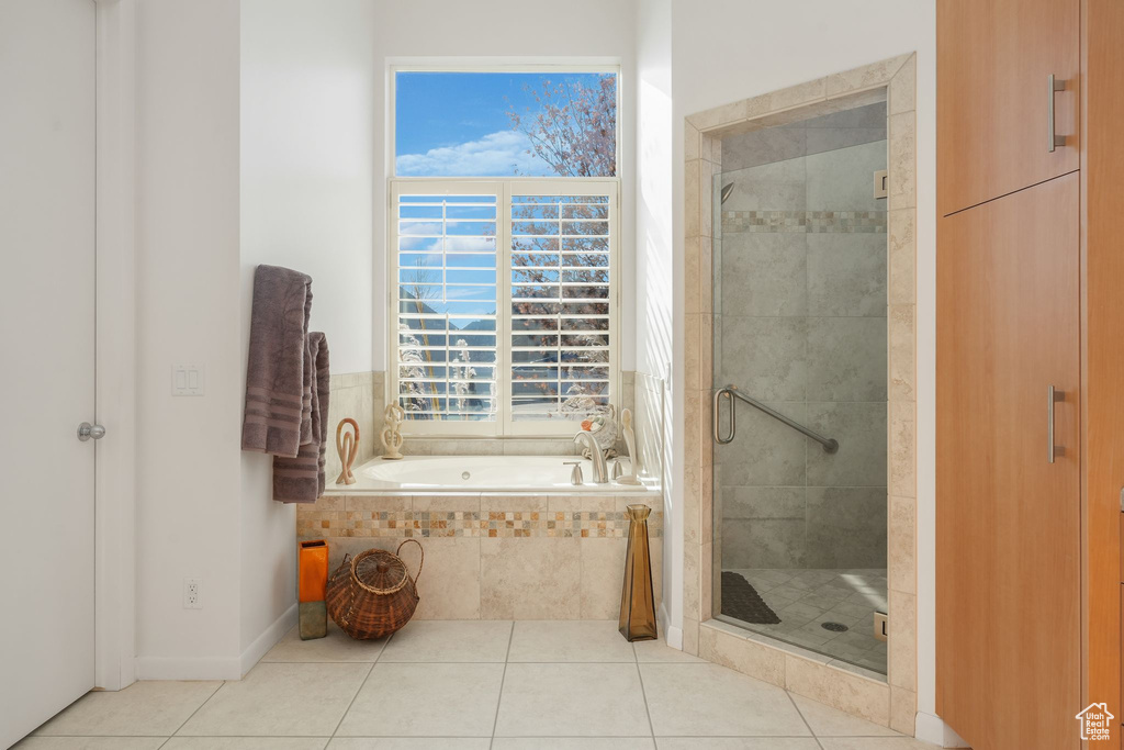 Bathroom featuring tile patterned flooring, a bath, a shower stall, and healthy amount of natural light