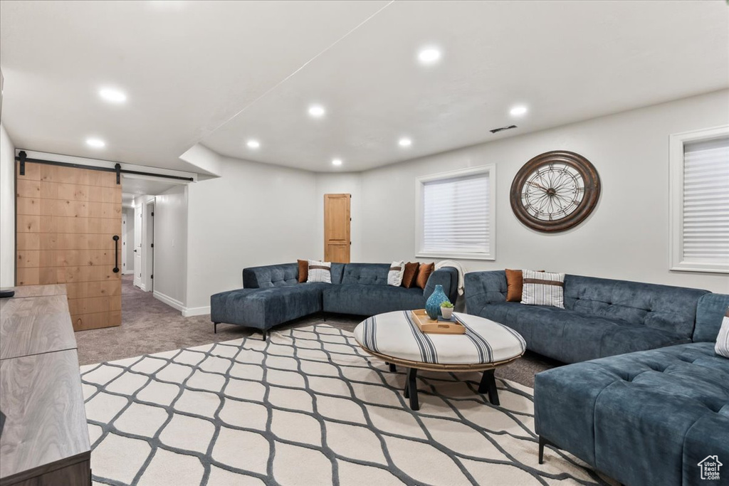 Living room featuring a barn door, light colored carpet, recessed lighting, and baseboards