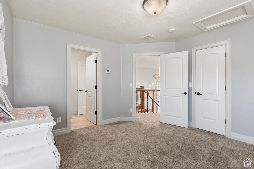 Unfurnished bedroom with carpet, baseboards, attic access, and connected bathroom
