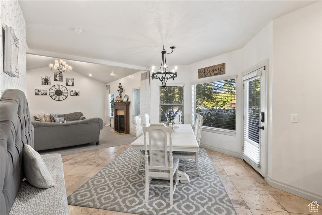 Dining area with a chandelier, healthy amount of natural light, baseboards, and lofted ceiling