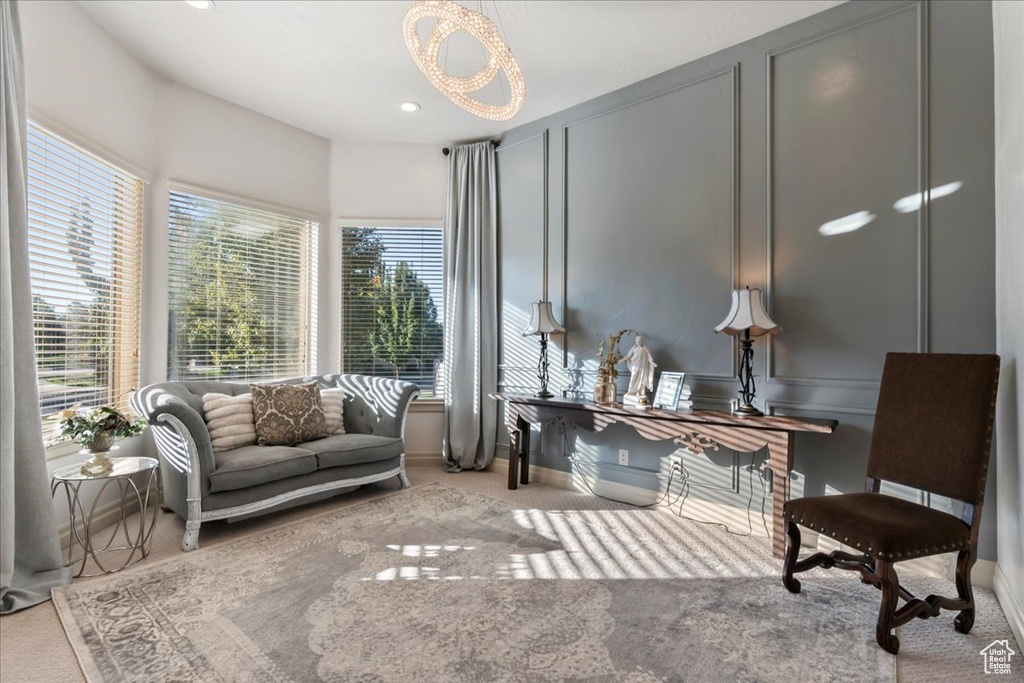 Living area featuring a chandelier, carpet, a decorative wall, recessed lighting, and baseboards