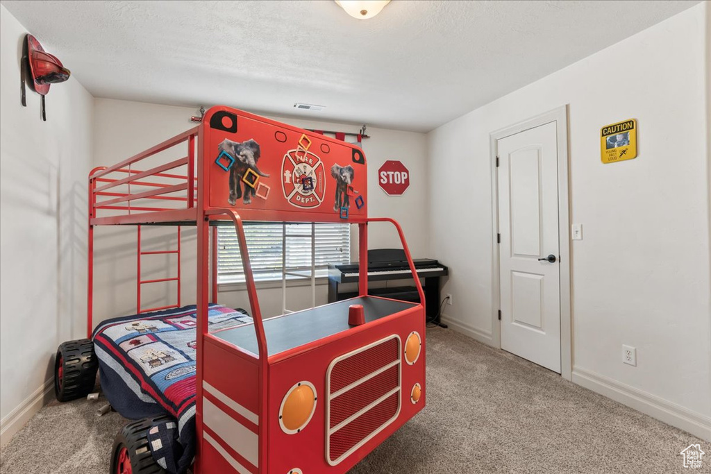 Carpeted bedroom featuring baseboards and a textured ceiling