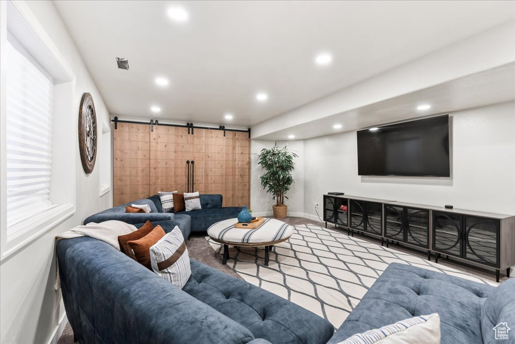 Carpeted living room with a barn door, recessed lighting, and baseboards