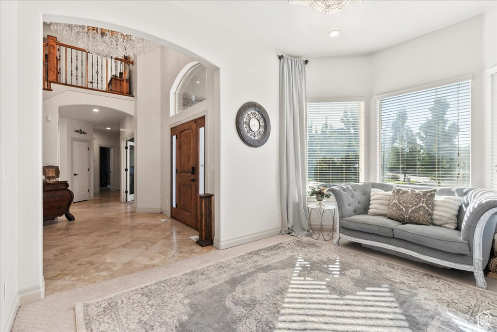Living area featuring arched walkways, baseboards, recessed lighting, and a towering ceiling