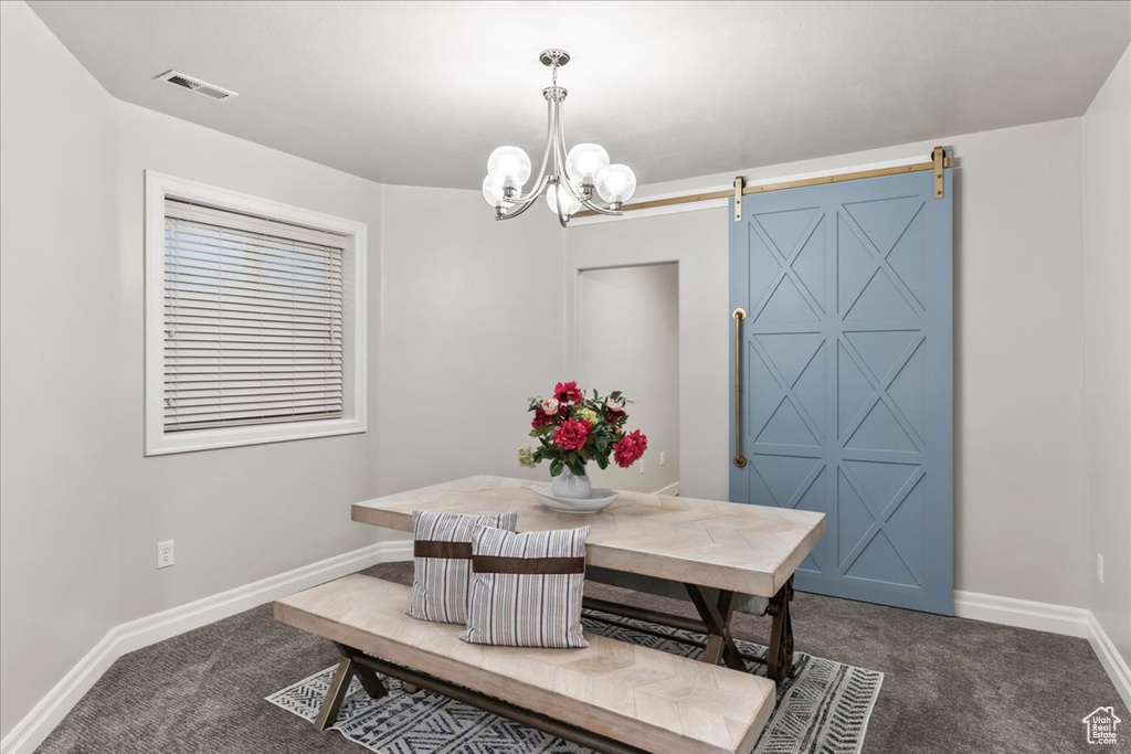 Dining area featuring dark colored carpet, a barn door, baseboards, and a chandelier