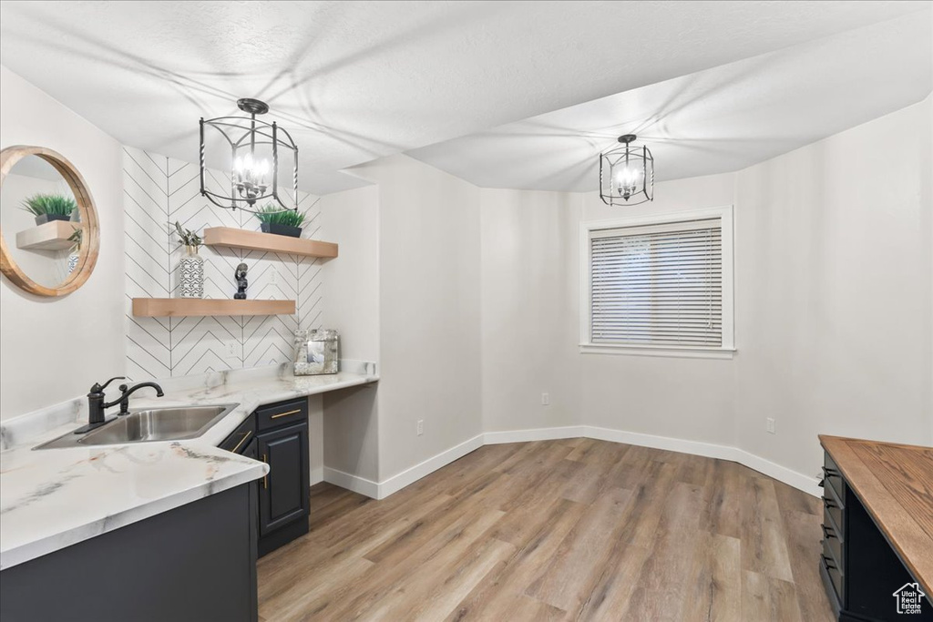 Kitchen featuring a sink, open shelves, a chandelier, and light wood-type flooring