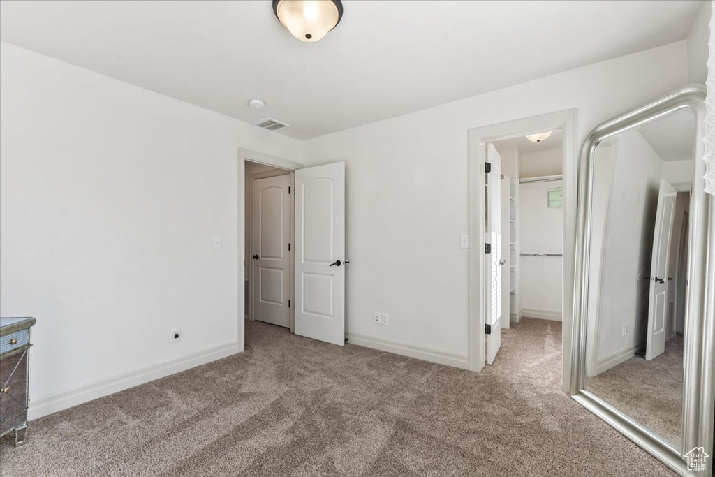 Unfurnished bedroom with carpet flooring, a spacious closet, and baseboards