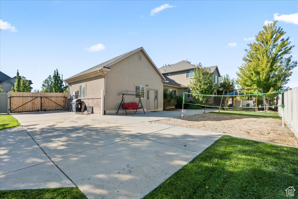 Rear view of property featuring volleyball court, stucco siding, and a gate