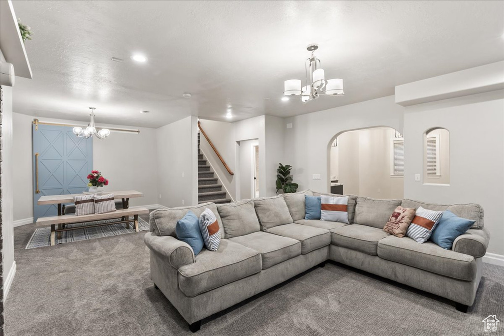 Carpeted living area featuring a chandelier, stairs, and baseboards