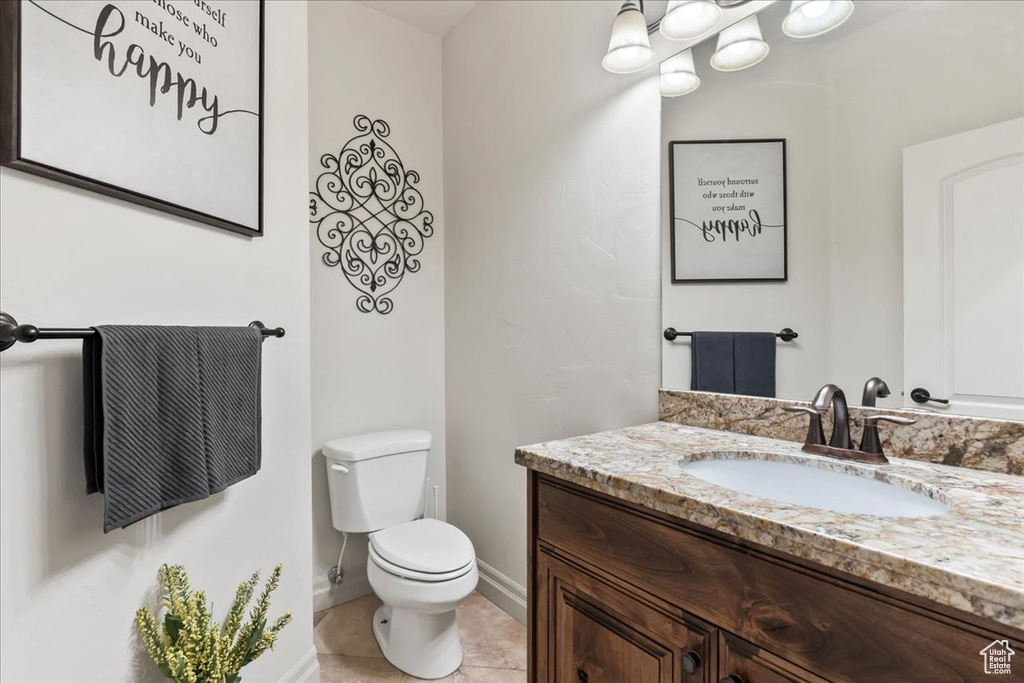 Half bath with vanity, toilet, tile patterned floors, and baseboards