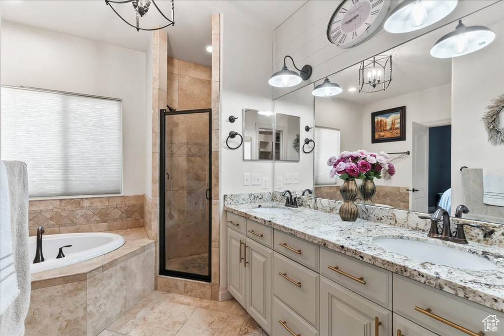 Bathroom featuring a bath, a shower stall, double vanity, and a chandelier
