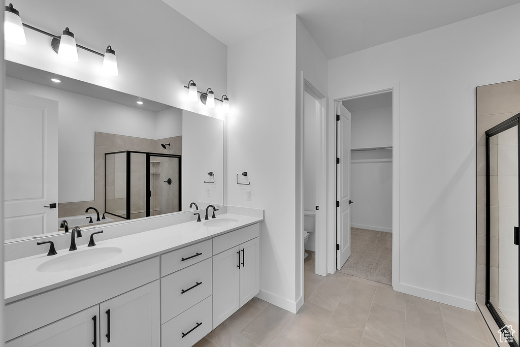 Full bath with a shower stall, double vanity, toilet, recessed lighting, and baseboards
