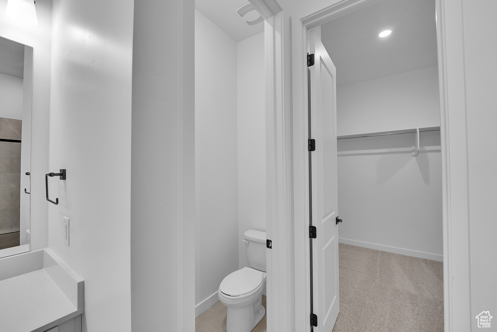 Bathroom with toilet, a spacious closet, vanity, and recessed lighting