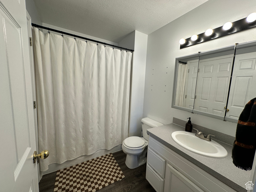 Full bath featuring toilet, vanity, a textured ceiling, and wood finished floors