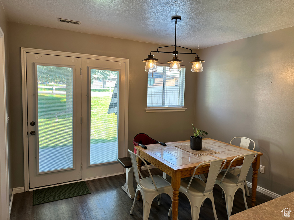 Dining space with a textured ceiling, dark wood-style floors, and baseboards