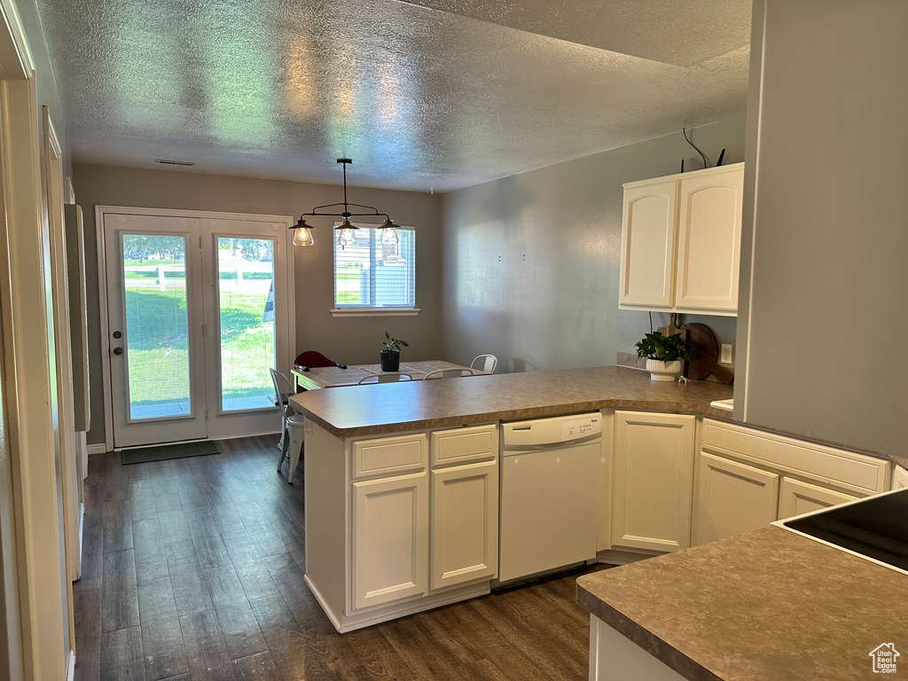 Kitchen featuring dishwasher, a peninsula, a textured ceiling, dark wood-style flooring, and white cabinetry