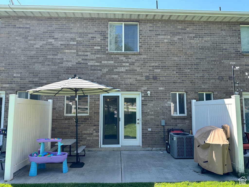 Rear view of house with cooling unit, a patio, and brick siding