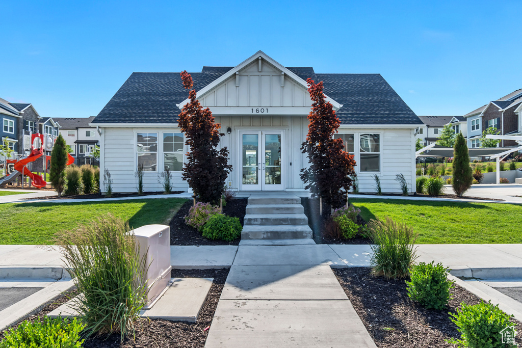 View of front of house with french doors, board and batten siding, a front lawn, and a shingled roof