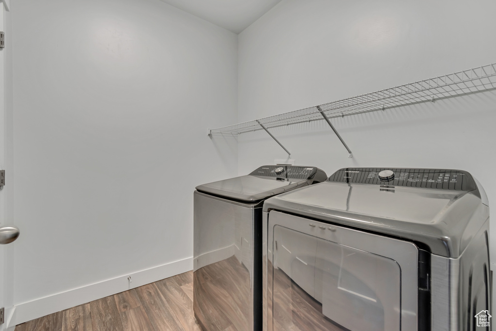 Laundry area featuring washer and clothes dryer, baseboards, and wood finished floors