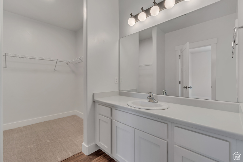 Bathroom with vanity, baseboards, and a walk in closet