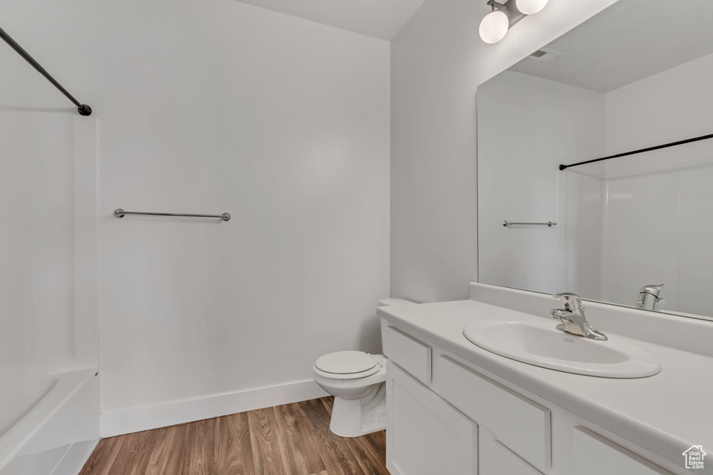 Bathroom with vanity, toilet, wood finished floors, shower / bathtub combination, and baseboards