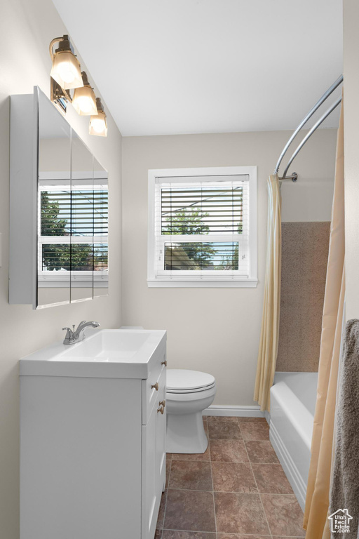 Bathroom with vanity, toilet, shower / bath combo, and baseboards