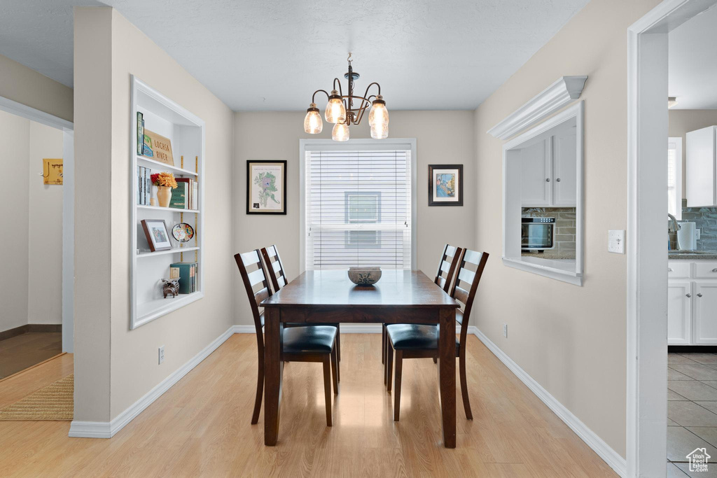 Dining area featuring a chandelier, light wood finished floors, built in features, and baseboards