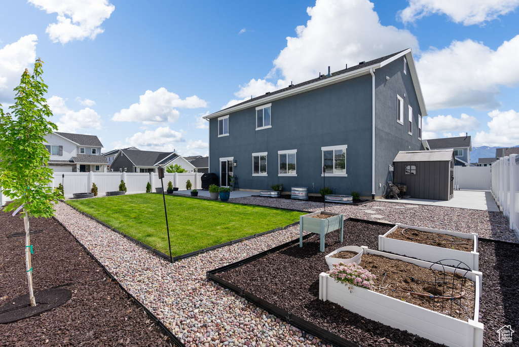 Back of property featuring a garden, a residential view, stucco siding, and a patio
