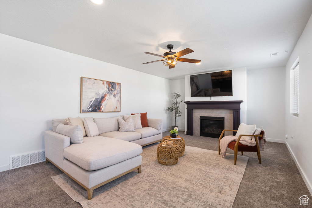 Carpeted living area featuring a glass covered fireplace, a ceiling fan, and baseboards