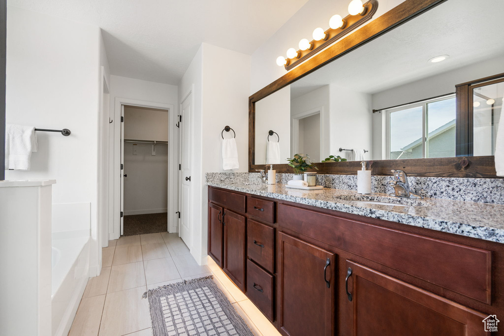 Full bath featuring double vanity, a garden tub, tile patterned flooring, an enclosed shower, and a walk in closet
