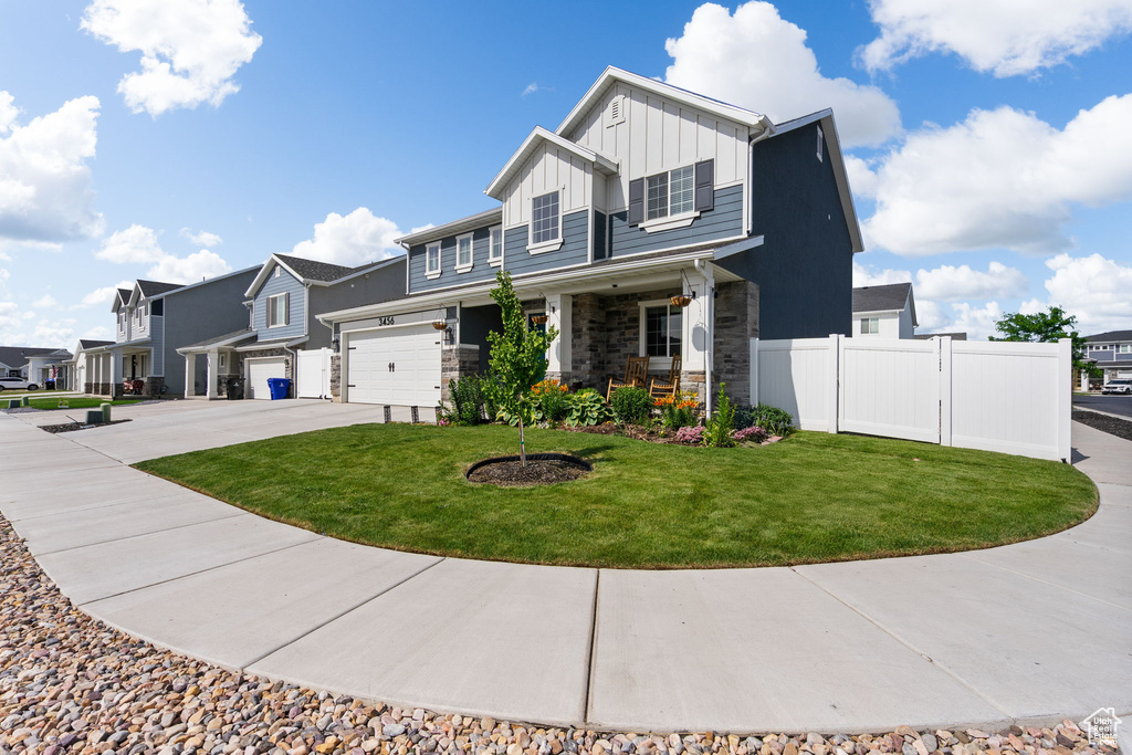View of front of home with board and batten siding, driveway, a porch, stone siding, and a residential view